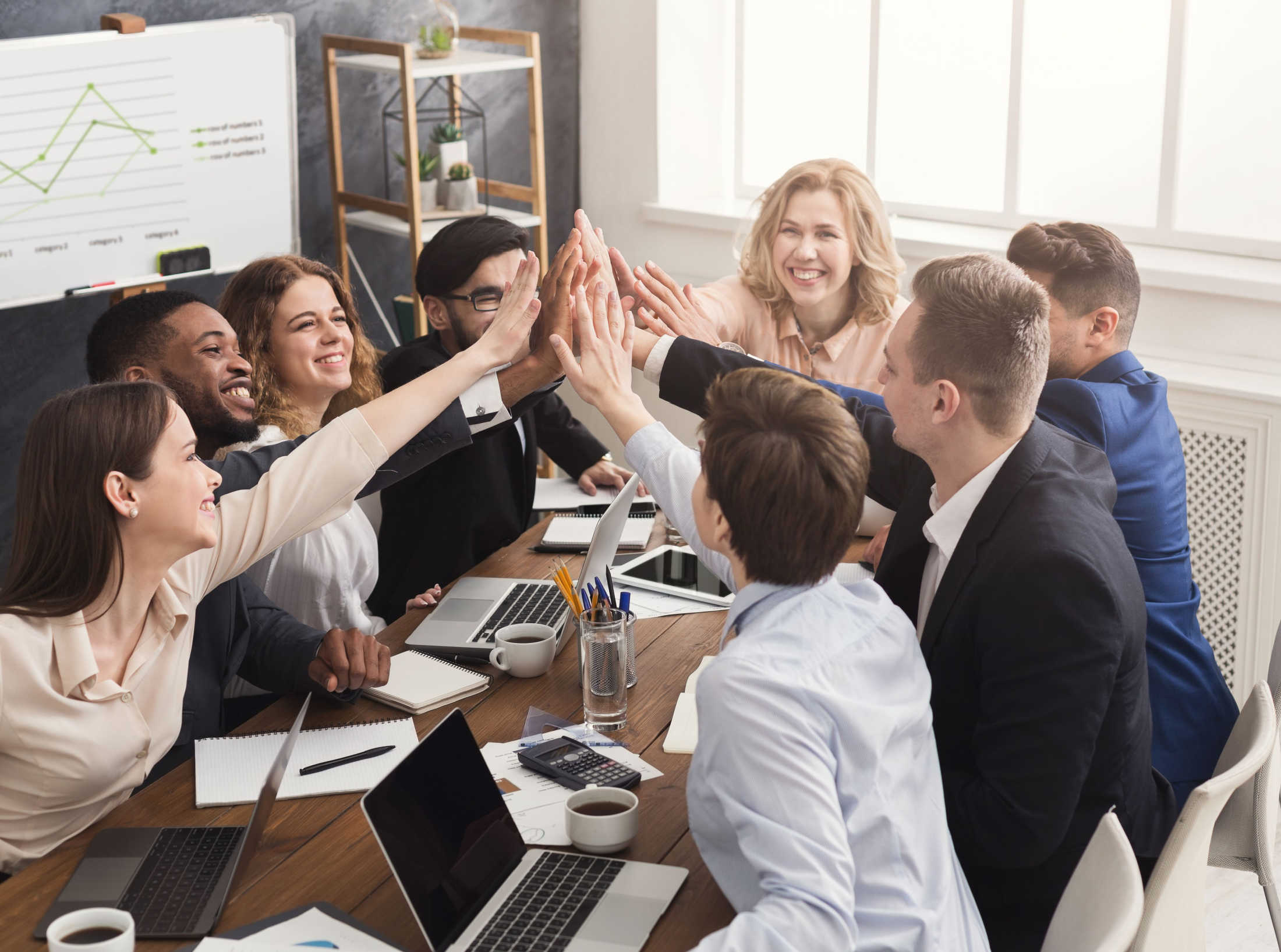 Group of co-workers high fiving success
