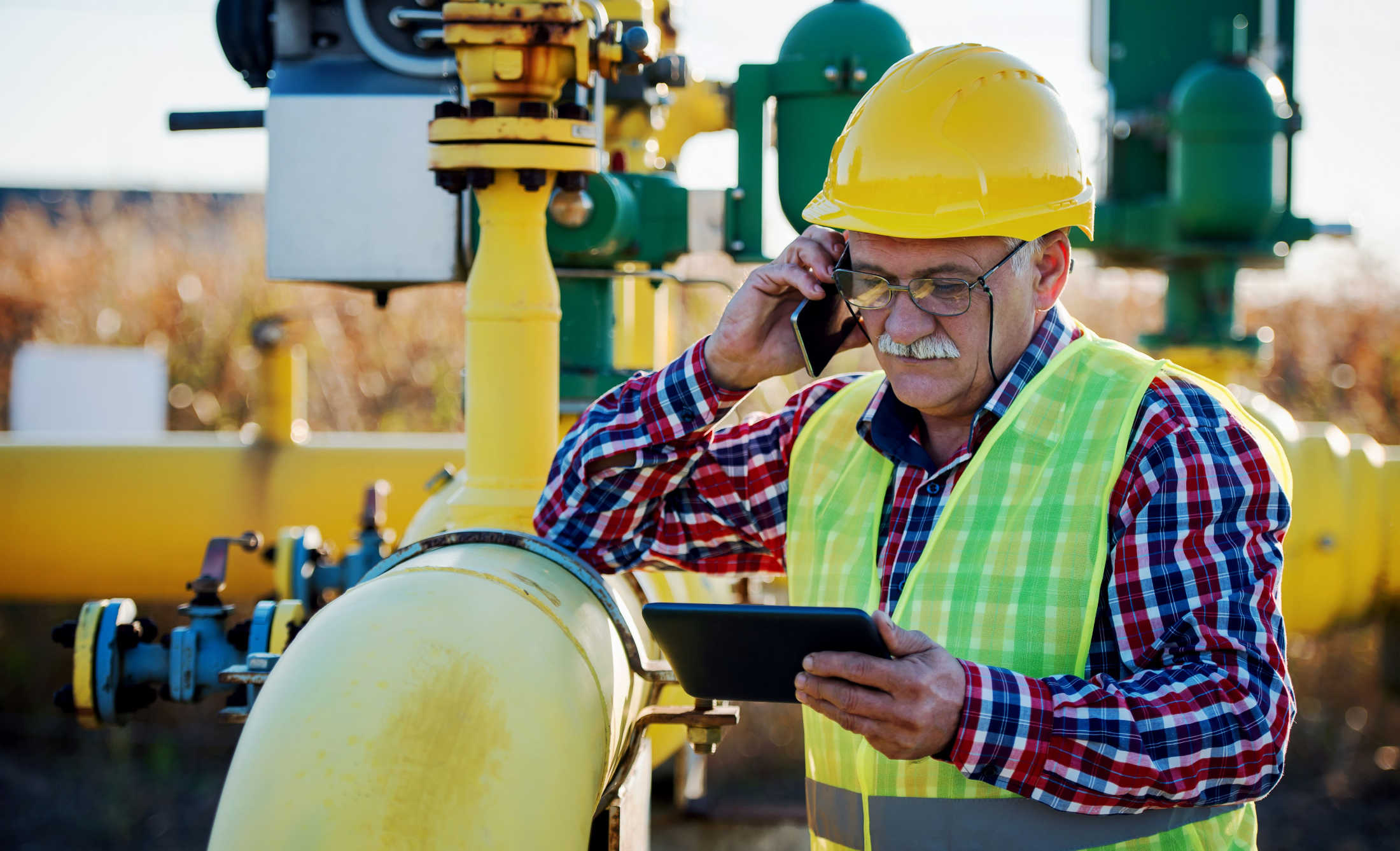 Site supervisor making a call on his mobile device while reviewing sensitive data on a tablet.